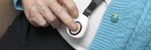 Elderly woman demonstrating call button worn on neck strap