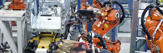 Vehicle factory manufacturing with robotic arms and automation.