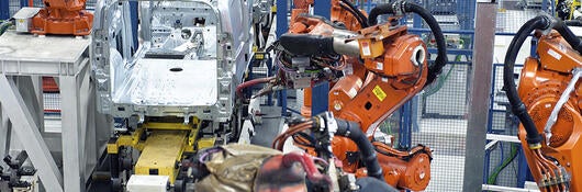 Vehicle factory manufacturing with robotic arms and automation.