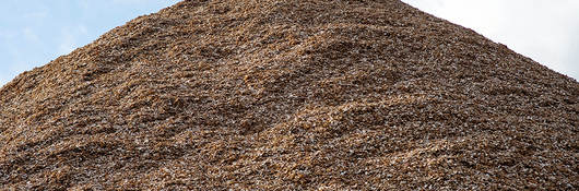 Pile of mulch woodchips against a blue sky