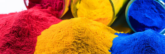 Magenta, yellow and cyan powders spill out of glass jars next to each other.