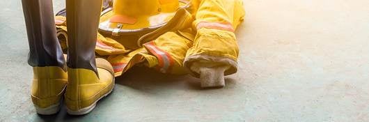 A yellow fireman’s uniform and boots laying on the ground. 