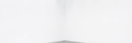 A black bench set in the middle of a white room.
