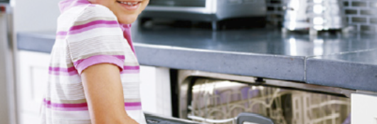 school age girl in a home kitchen opening dishwasher