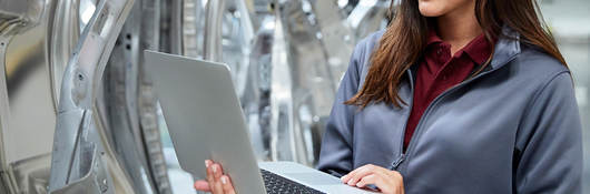 Woman with a laptop inspecting an automotive factory.