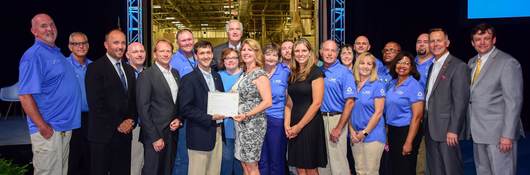The BASF Zero Waste team stands in front of a mock-up of their facility as they accept their Zero Waste certification.