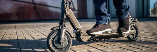 close up view of the legs of a man on an electric scooter.