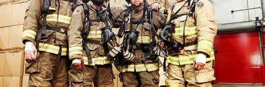 UL firefighters show off their gear in front of a mock warehouse. 