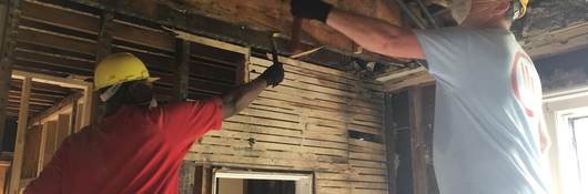 UL volunteers tear down wood furring in historic Elgin, Illinois home.
