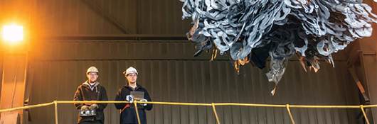 2 men overlooking a claw picking up recycleables