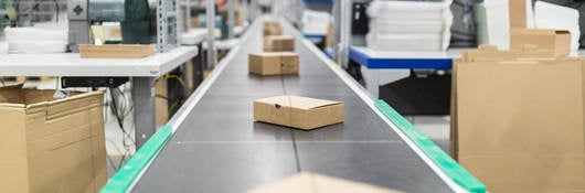 Cardboard boxes on conveyor belt at distribution warehouse