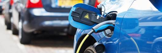 Blue electric vehicle is charging on a city street.
