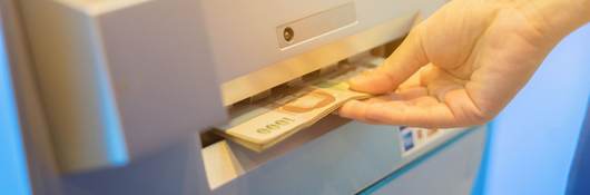 Hand accepts money dispensed from ATM machine