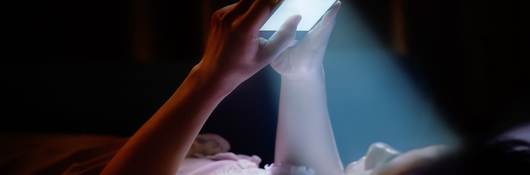 Blue light filters onto a mobile phone user as she surfs for information.