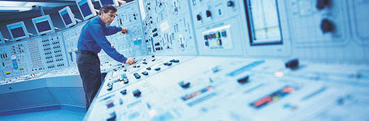 Man standing over industrial controls panel