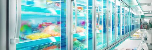 A row of supermarket freezers filled with all types of refrigerated food.