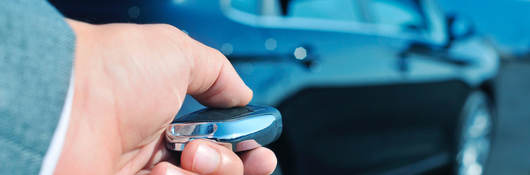 A man approaches a car with a key fob in his hand.