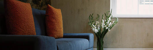 Photo of a blue couch with orange throw pillows