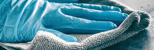 Photo of a person wearing gloves sanitizing a surface