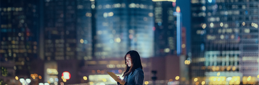 Woman looking at her tablet at night in the city