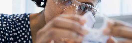 Woman scientist with safety glasses doing testing