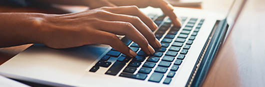 Photo of a person typing on a laptop
