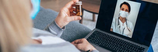 Senior woman isolated at home due to coronavirus epidemic having video call with family doctor, consulting about medicine