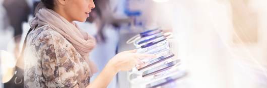 Consumer looking at several mobile devices in retail setting