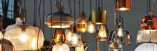 Variety of lamps and lightbulbs hanging from ceiling 