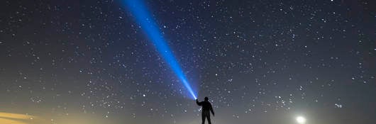 Flashlight illuminating a starry sky