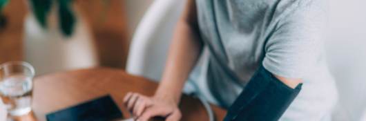 Woman measuring blood pressure and checking parameters via smartphone