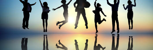 Group of people jumping in front of a sunset