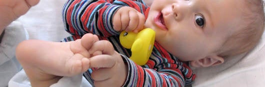 Baby lying down playing with toys