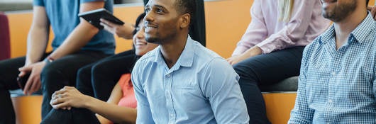 Group of people smiling with laptops while sitting in auditorium