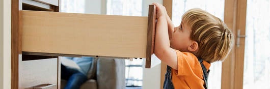 A child pulling on an open dresser drawer, a furniture tip-over risk