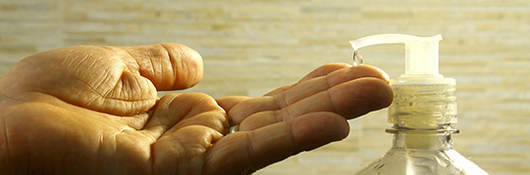 Hand held out under hand sanitizer nozzle 