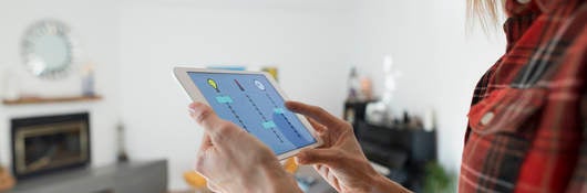 Woman controlling home utilities with digital tablet.