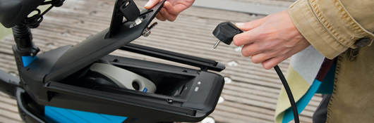 Woman charging electric bike outdoors