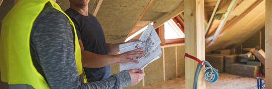 Workers discussing blueprints in an attic
