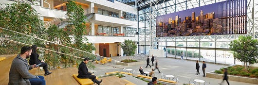 multi-storey atrium in commerical office building with people on wooden benches
