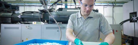 Worker inspecting recycled plastic in plastics factory