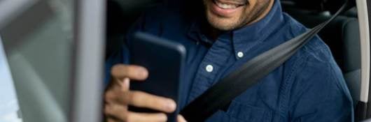 man sitting in car looking mobile driver license on smartphone
