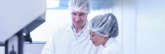 Man and woman scientists inspecting product in pharmaceutical factory