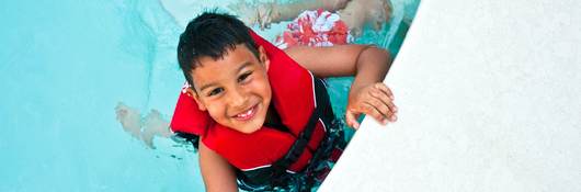 Smiling boy wearing lifejacket in swimming pool