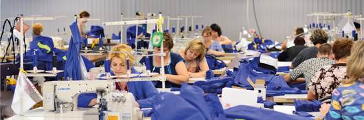 Tailors sewing blue fabric in a factory setting
