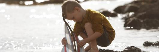 Young boy playing with a toy sailboat