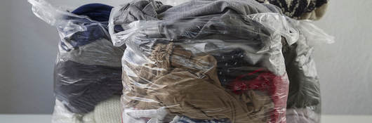 Clothes in plastic bags conveying promotion of recycling clothing, give it second life than become waste