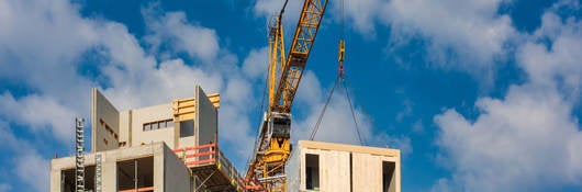 Crane lifting a prefabricated wooden building module to its position in the structure