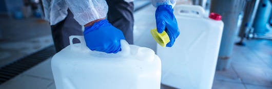 working with chemicals - person putting a yellow cap on a plastic chemical container