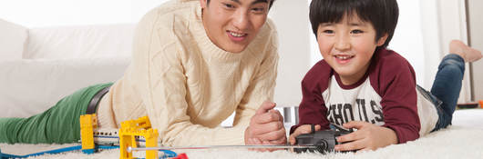 father and son on floor playing with toy train